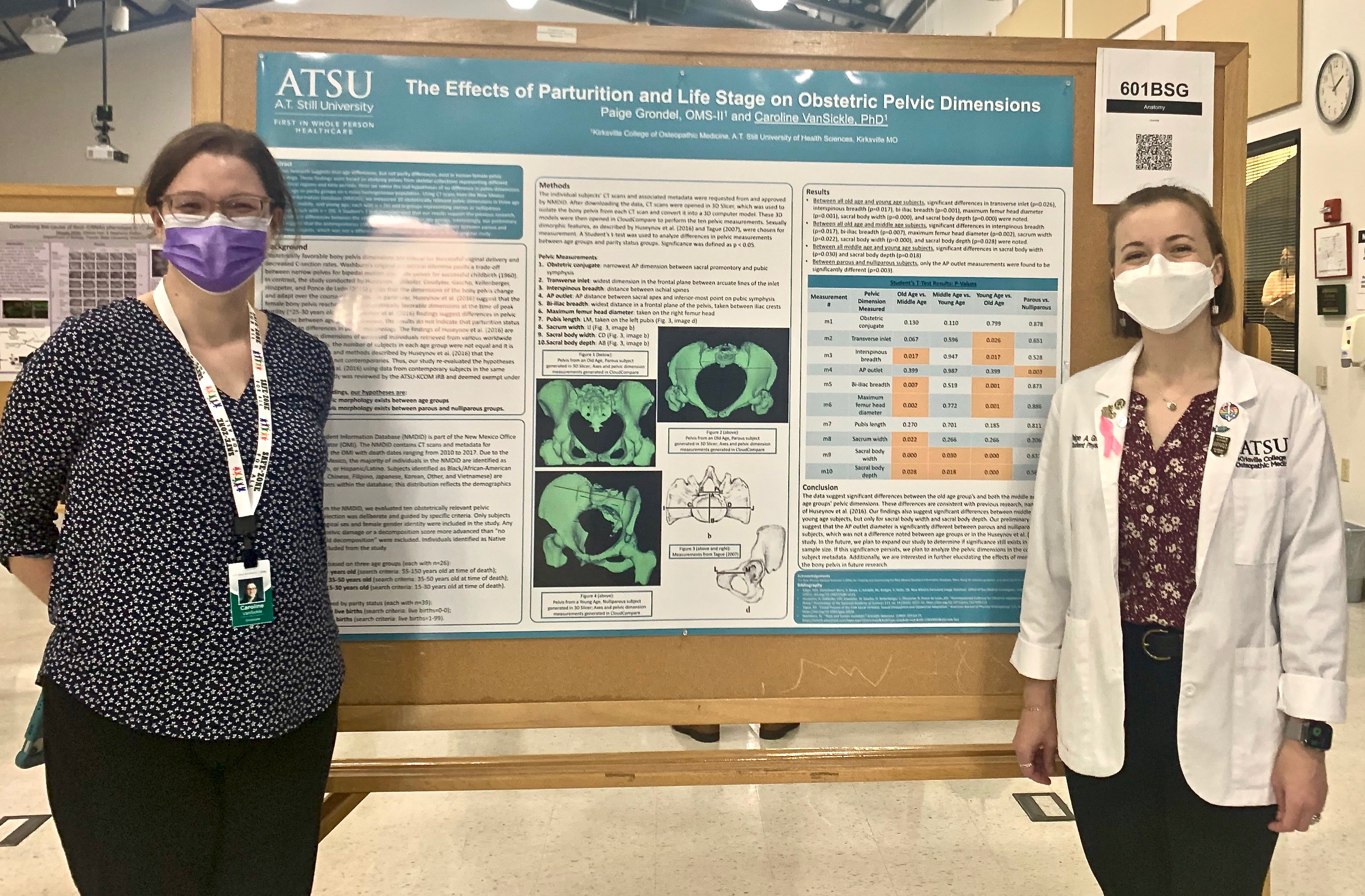Two women standing in front of a conference-style poster entitled 'The Effects of Parturition and Life Stage on Obstetric Pelvis Dimensions'